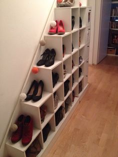 there are many pairs of shoes on the shelves next to the stairs in this room