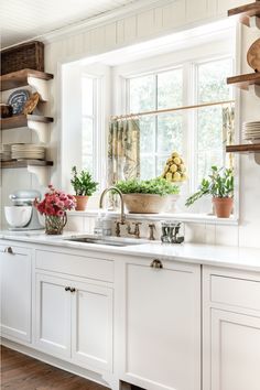 a kitchen filled with lots of white cupboards and counter top next to a window