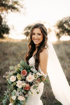 a woman in a wedding dress holding a bridal bouquet and smiling at the camera