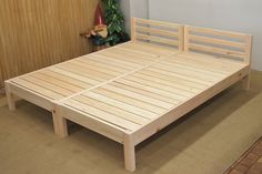 a wooden bed frame sitting on top of a floor next to a potted plant