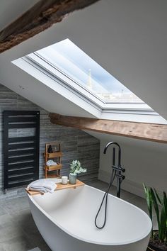 a white bath tub sitting under a skylight in a bathroom next to a window