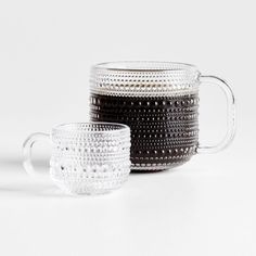 two glass mugs sitting next to each other on a white surface with black dots