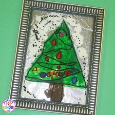 a christmas tree made out of paper on top of a green surface with silver frame