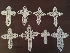 six crocheted crosses on a wooden table with white thread in the shape of flowers