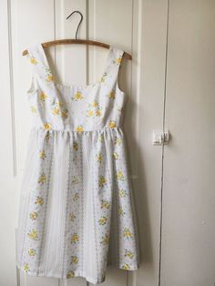 a white dress hanging on a wooden hanger in front of a door with flowers