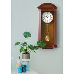 a clock mounted to the side of a wall next to a potted green plant