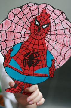 a child holding up a paper cut out of spiderman