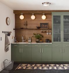 a kitchen with green cabinets and black flooring