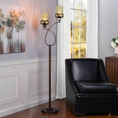 a living room with a black chair and two candles on the floor next to a window