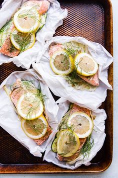 four fish fillets with lemons and dill garnish on parchment paper