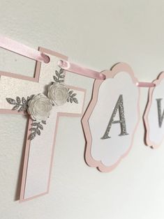 a pink and white banner with flowers hanging from it's sides on the wall