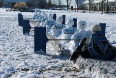 a man sitting on top of a bench covered in snow