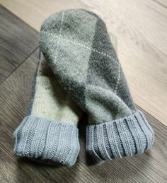 a pair of gray and white mittens laying on top of a wooden floor next to each other