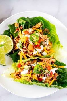 two lettuce wraps topped with shredded cheese and toppings on a white plate