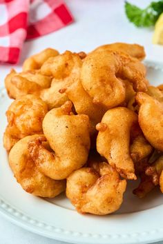 some fried food on a white plate next to lemon wedges