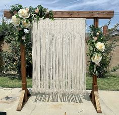 an outdoor wedding ceremony setup with white flowers and macrame hanging from the ceiling