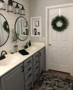 a bathroom with two sinks, mirrors and wreaths on the wall above it's doors