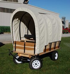 an old fashioned wagon is parked in front of a building with a white cover on it