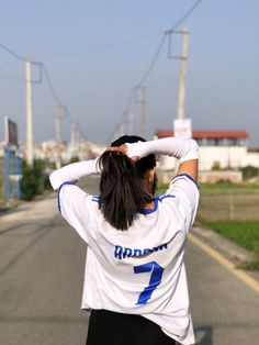 a woman standing on the side of a road holding her hair in one hand and covering her eyes with both hands