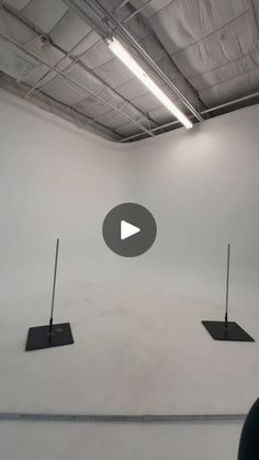 an empty room with three black poles in the center and one white wall behind it