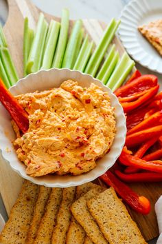 crackers, carrots and celery on a cutting board with hummus