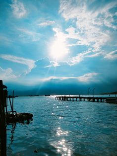 the sun shines brightly in the blue sky over the water and dock area at dusk