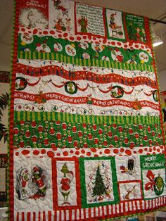 a christmas quilt hanging from the ceiling in front of a store window with santa's helpers on it