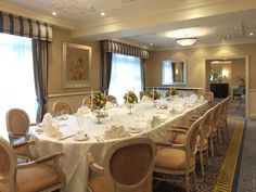 a long table with white linens is set up for a formal function in the ballroom