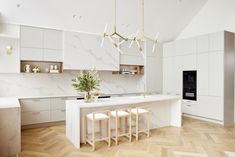 a large kitchen with white cabinets and marble counter tops, two stools at the island