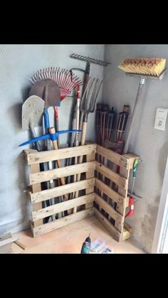 a wooden crate filled with gardening tools on top of a floor next to a wall