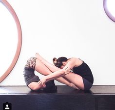 a woman sitting on top of a black table in front of a mirror with her legs crossed