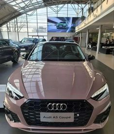 an audi car is parked in a showroom with other cars on display behind it