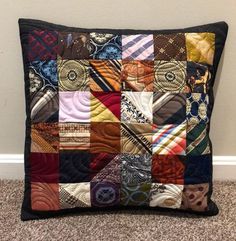 a black pillow with many different colored ties on it