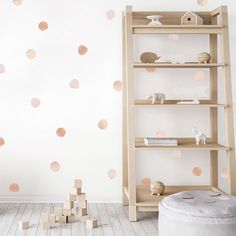 a white room with pink polka dot decals on the wall and wooden bookshelves