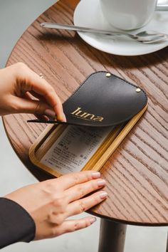 a person cutting up a piece of luggage on top of a wooden table next to a cup and saucer