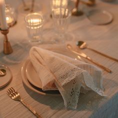 the table is set with silverware and white linen napkins, gold cutlery