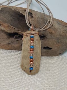 a piece of wood with beads hanging from it's end on a rope necklace