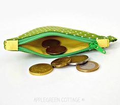 coin purse with green polka dot lining and gold coins in the bottom half, sitting on a white surface