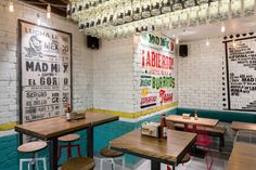 the interior of a restaurant with wooden tables and stools in front of a brick wall