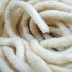 closeup of white wool yarn that has been rolled up and turned into something interesting