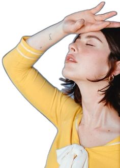 a woman with her eyes closed wearing a yellow shirt and white gloves is holding her hands up to her head