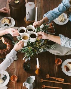 several people are sitting at a table with coffee and pastries on the table top