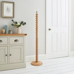 a tall wooden floor lamp sitting on top of a hard wood floor next to a white door