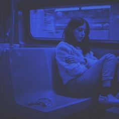 two women sitting on a subway train looking out the window at something in the distance