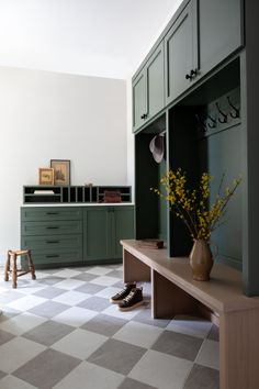 a room with green cabinets and checkered flooring on the floor, including a bench