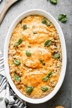 a casserole dish with cheese and spinach leaves on top, in a white bowl