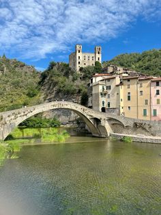 a bridge over a river with buildings on the hill in the background