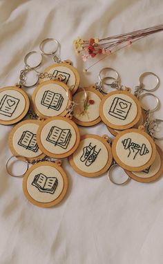 eight embroidered keychains with symbols on them sitting on a white cloth covered surface