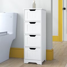 a white cabinet next to a toilet in a room with yellow trim on the walls