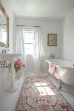 a white bathroom with pink flowers on the rug in front of the bathtub and sink